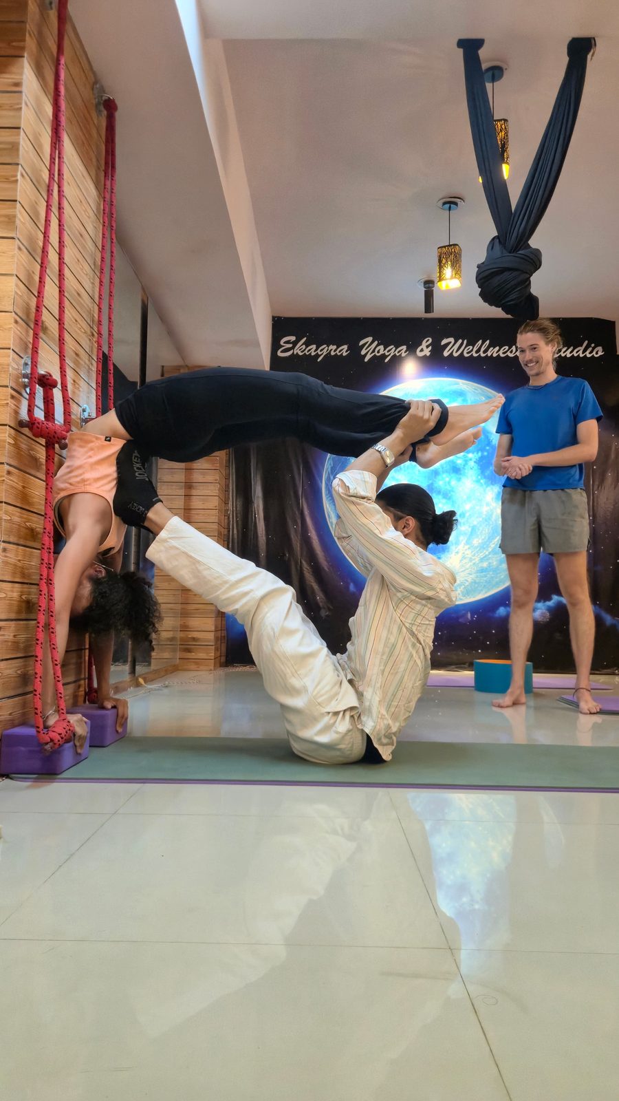 Yoga Master Deepanshu supporting a student in an inverted partner balance