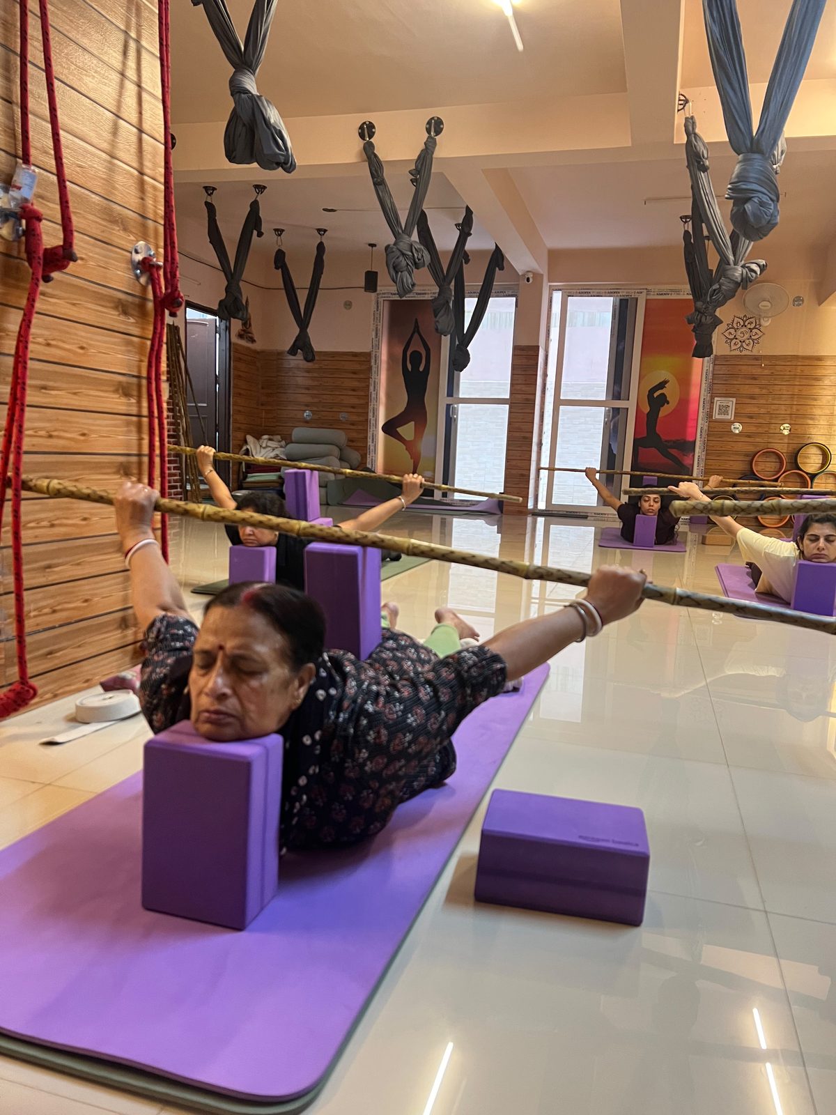 Class practising Locust Pose with blocks at the bamboo bar